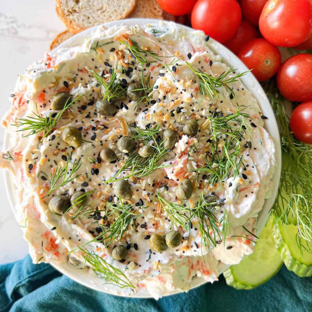 Smoked salmon spread topped with capers and fresh dill in a white bowl.