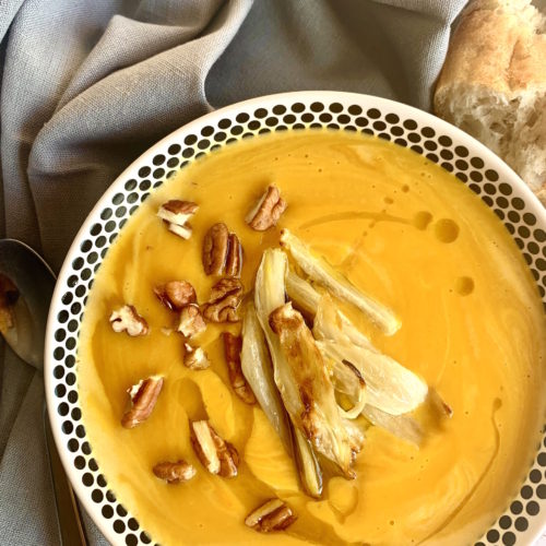 Bowl of red kuri squash soup, topped with roasted fennel, toasted pecans and a drizzle of olive oil