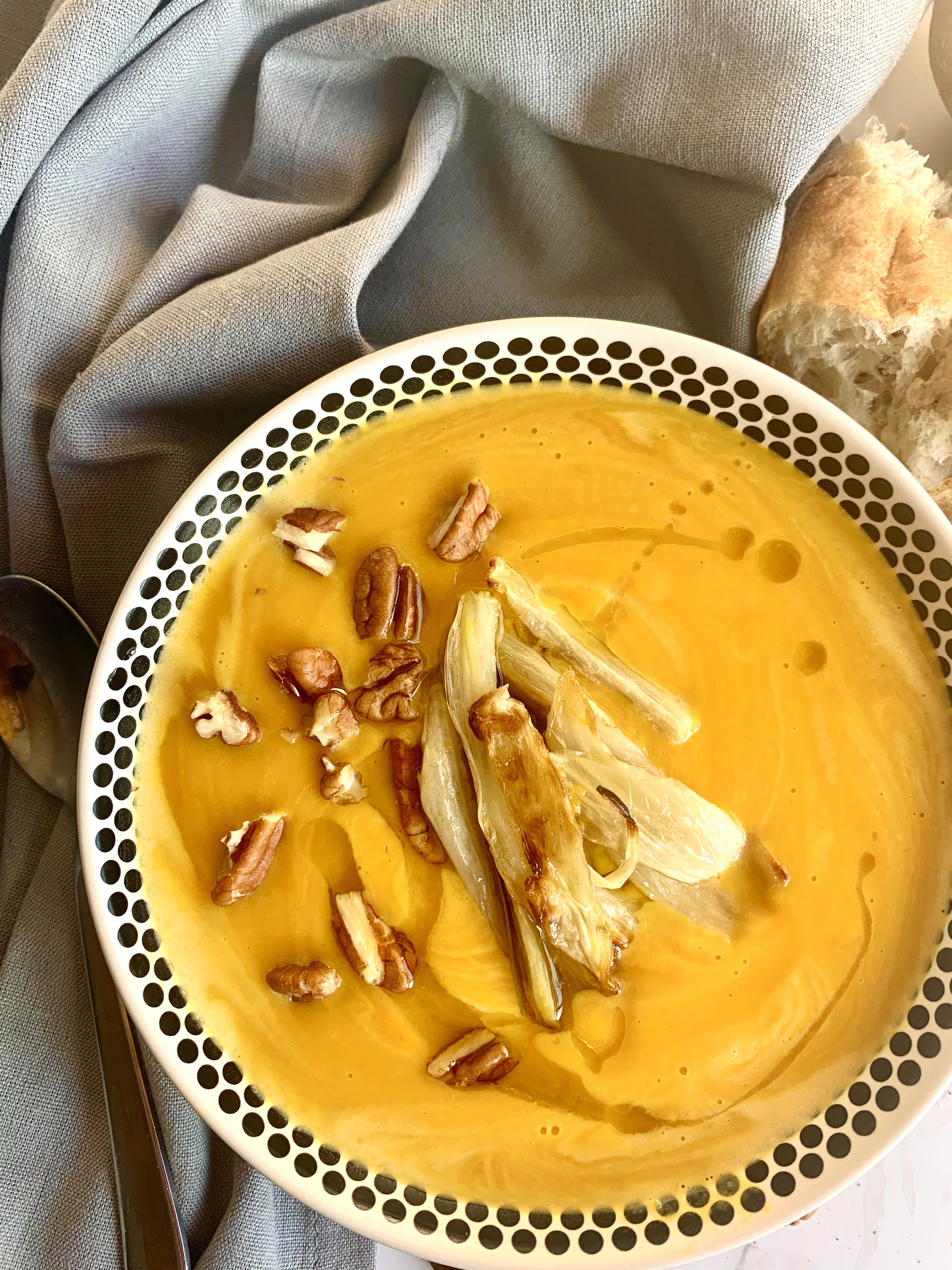 Bowl of red kuri squash soup, topped with roasted fennel, toasted pecans and a drizzle of olive oil