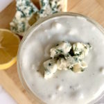 Greek yogurt blue cheese dressing in a jar with blue cheese crumbles and lemon in the background