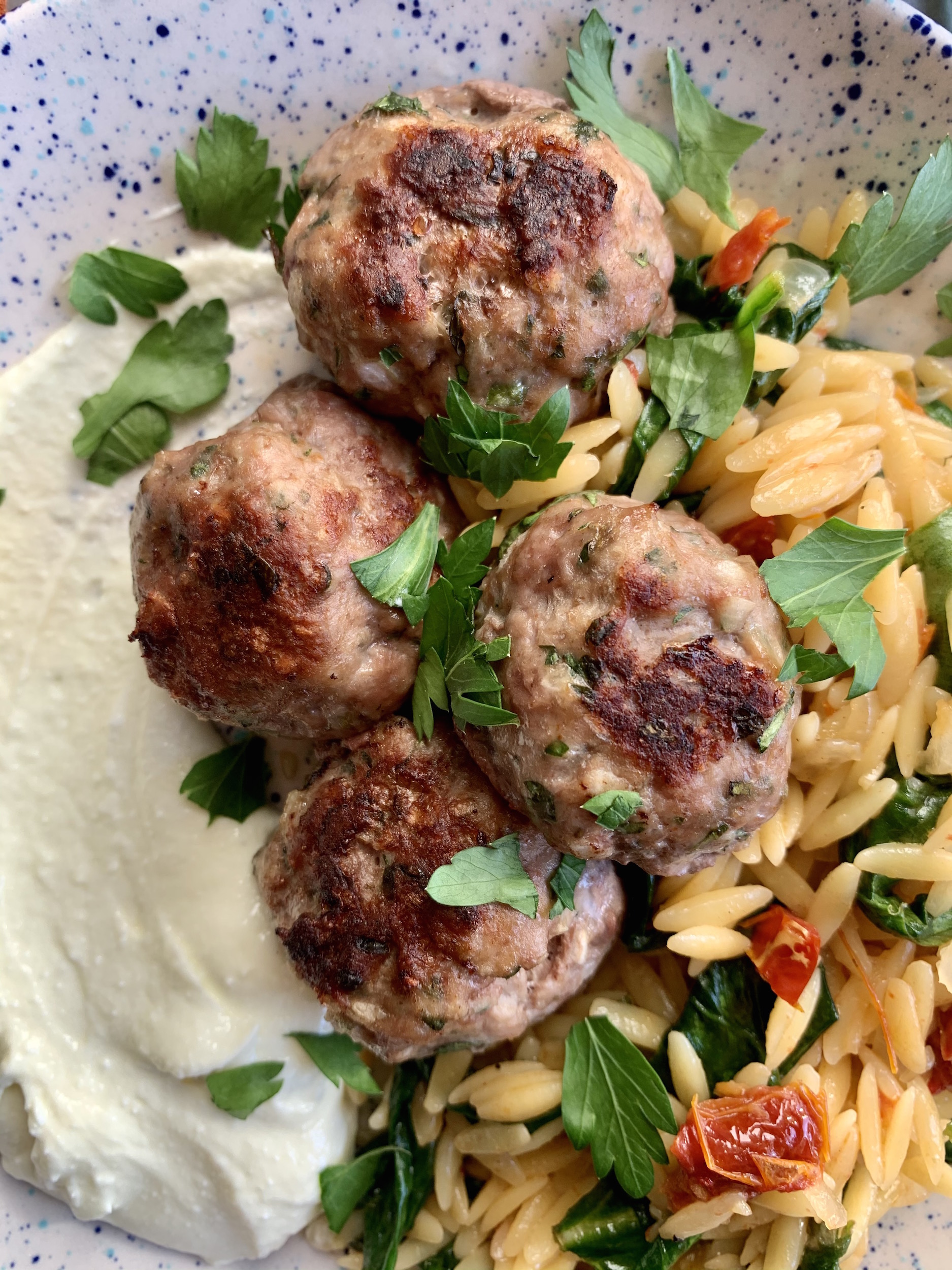 close up of greek meatballs with orzo and whipped feta
