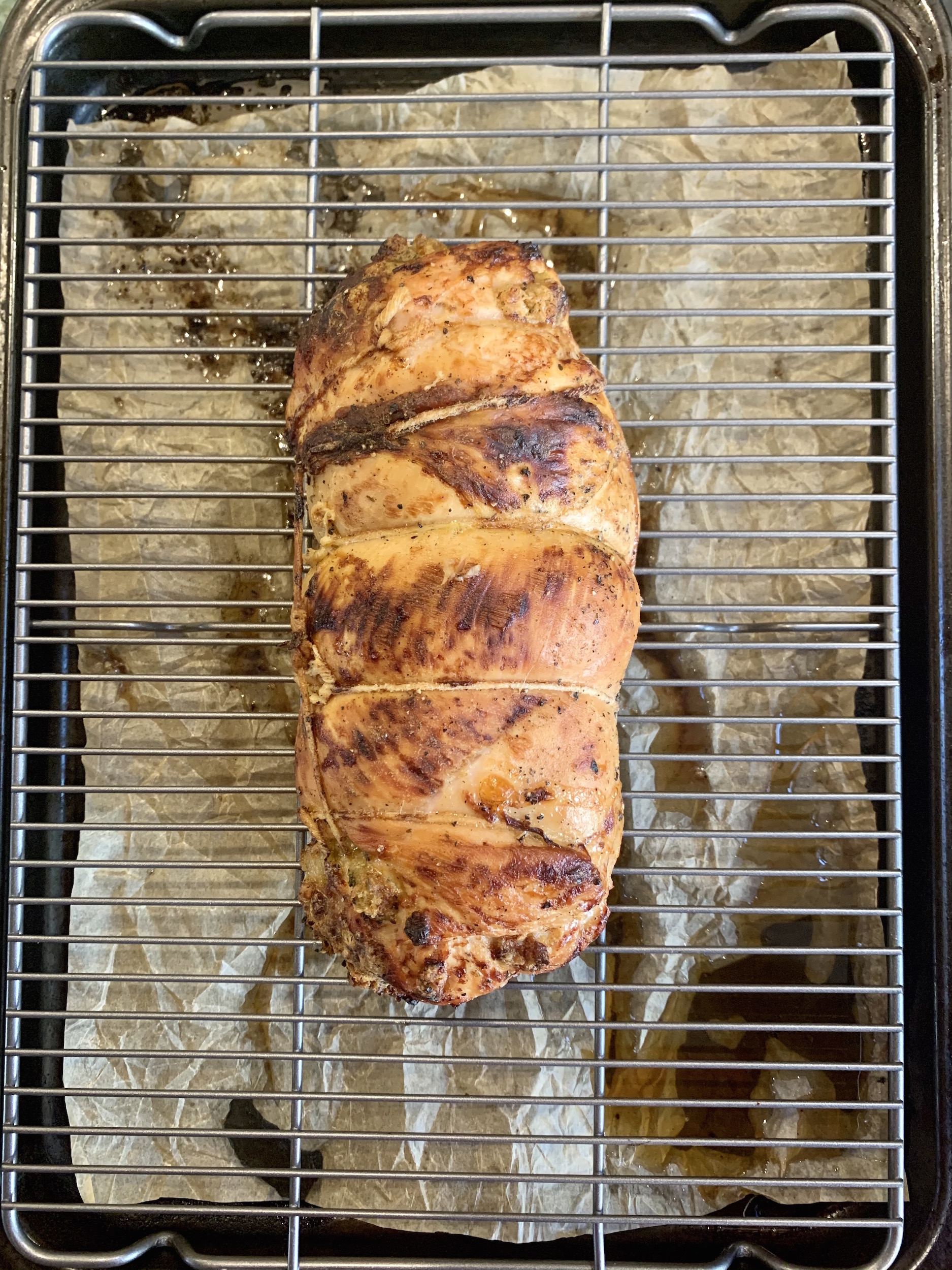 Roasted whole turkey roulade on baking sheet with rack