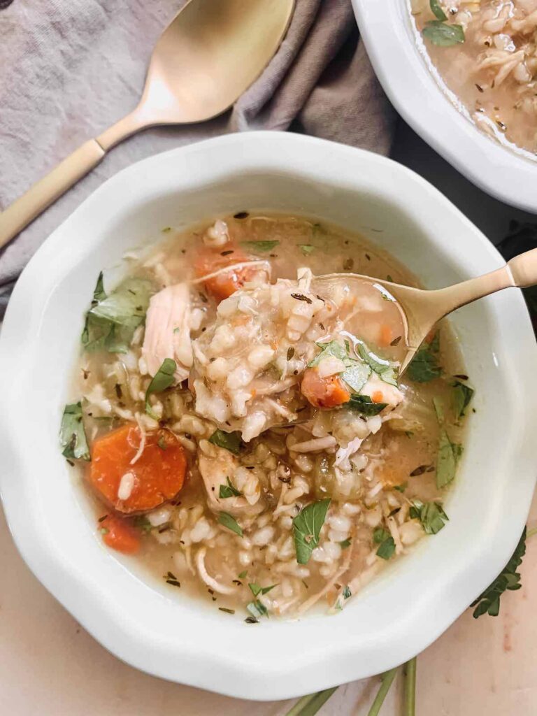 Bowl of Instant Pot Chicken and Rice Soup with a spoonful of soup on a gold spoon.