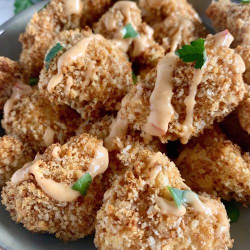 Close up of crispy, panko breaded cauliflower florets drizzled with bang bang sauce