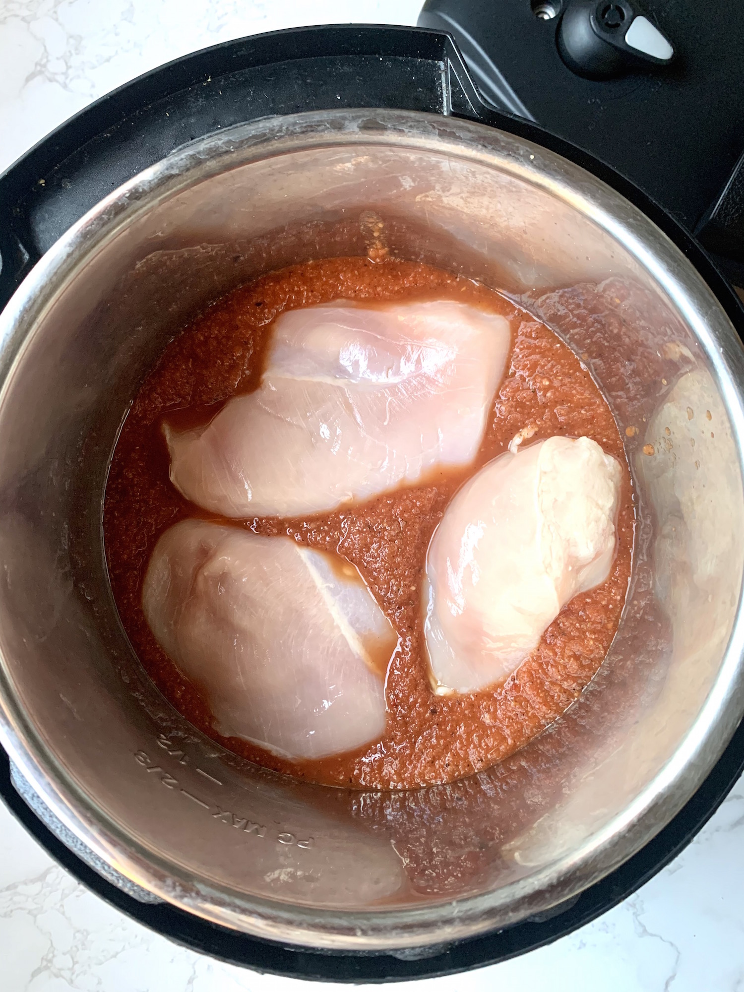 Instant pot with tinga sauce and whole raw chicken breasts