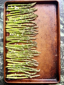 Cooked asparagus on half of a sheet pan