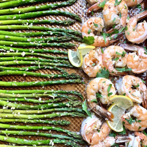 Asparagus and shrimp with lemon slices on a baking sheet