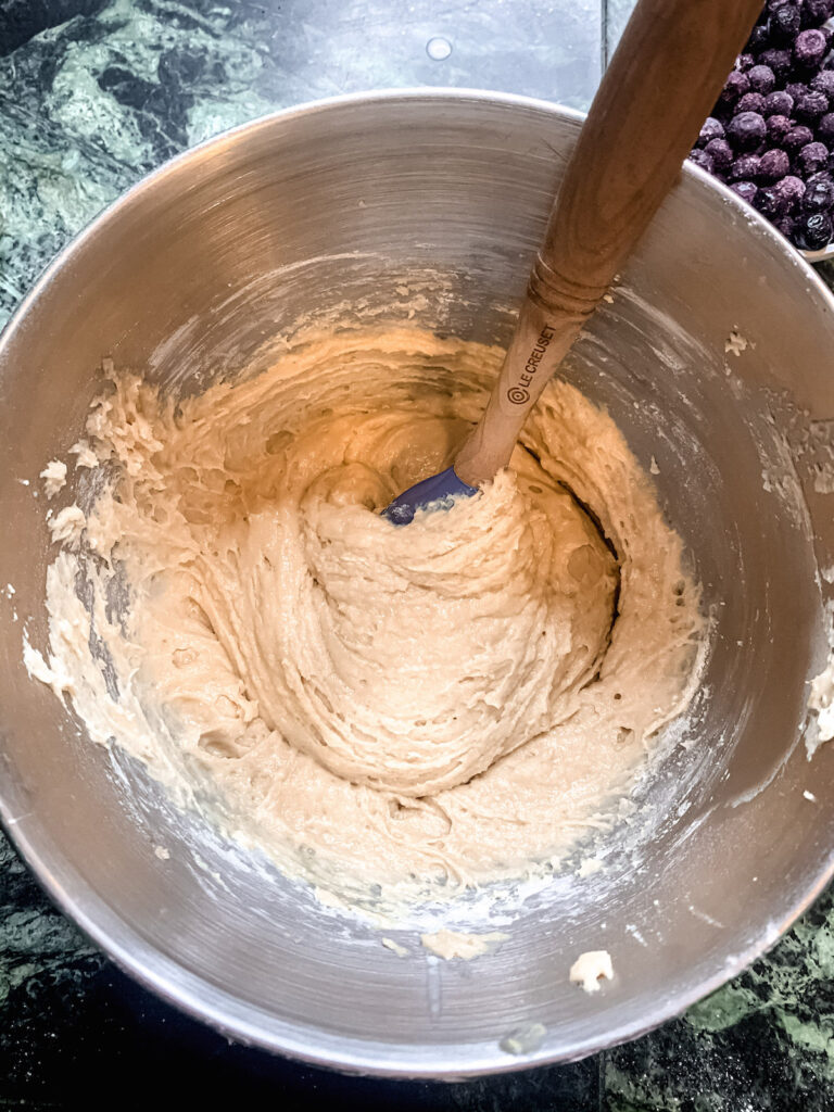 Buttermilk muffin batter without blueberries in a metal stand mixer bowl with a blue spatula