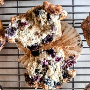 Close up of split buttermilk blueberry muffin on a wire rack