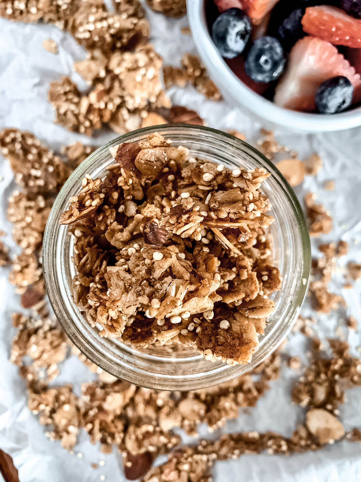 Vanilla almond granola in a mason jar with berries in background.