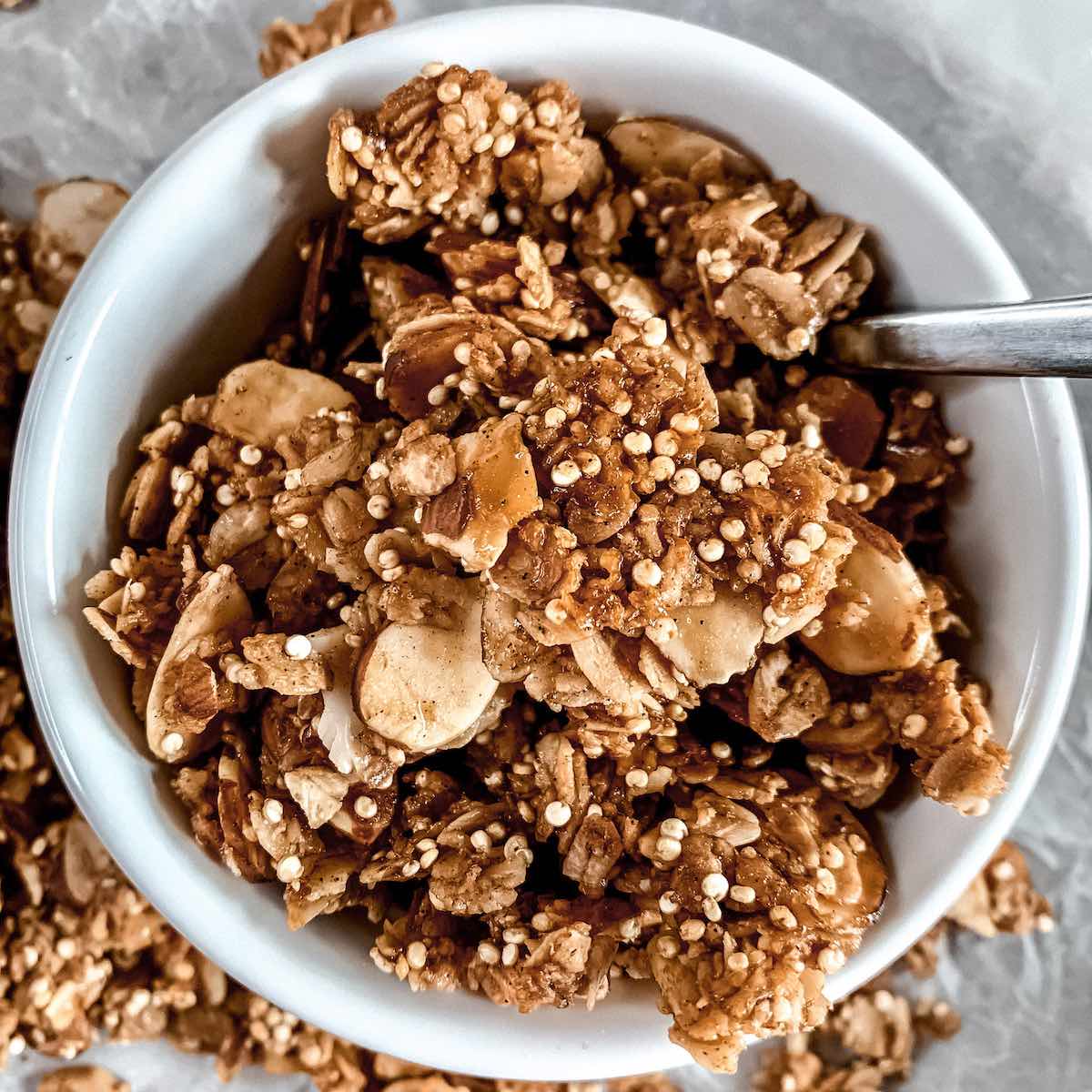 Homemade granola in a white bowl with a spoon.