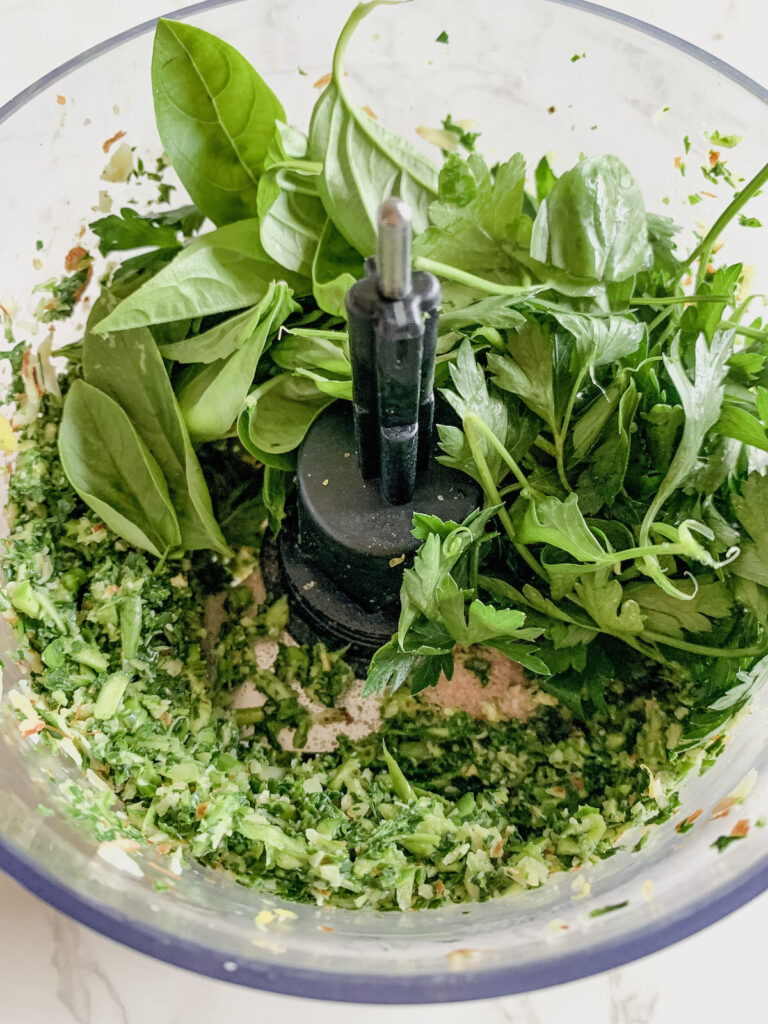 Adding herbs to bowl of food processor