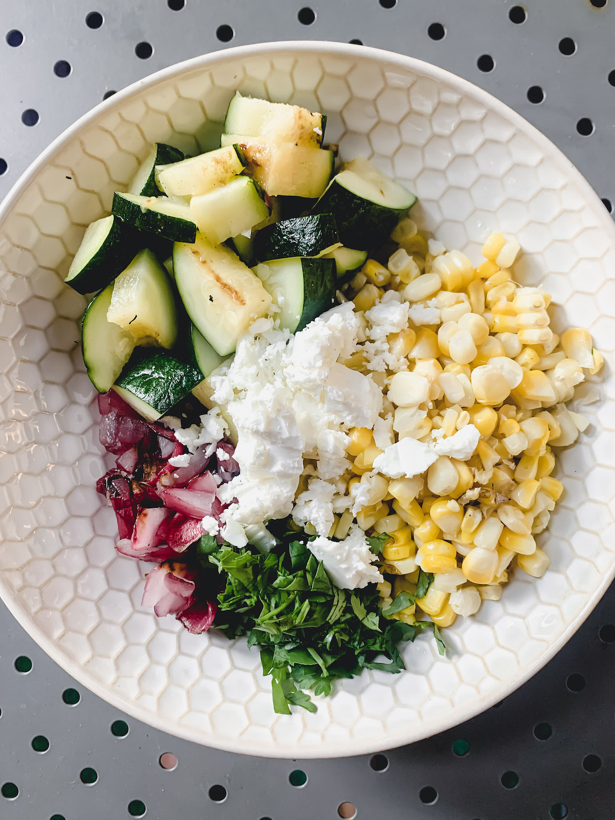 Grilled Corn and zucchini salad ingredients in a honeycomb patterned bowl