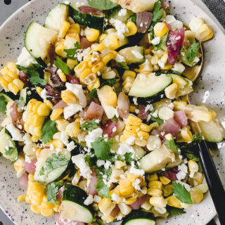 grilled corn, zucchini, red onion, feta and herbs chopped and mixed together in a speckled dish