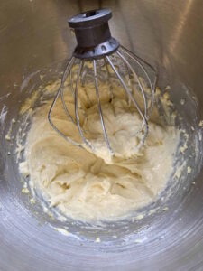 Cream cheese filling in a metal stand mixer bowl with whisk attachement.