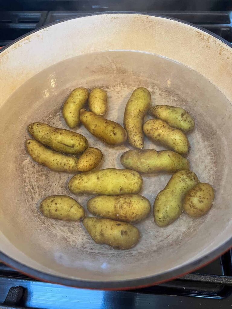 Fingerling potatoes boiling in a red dutch oven.