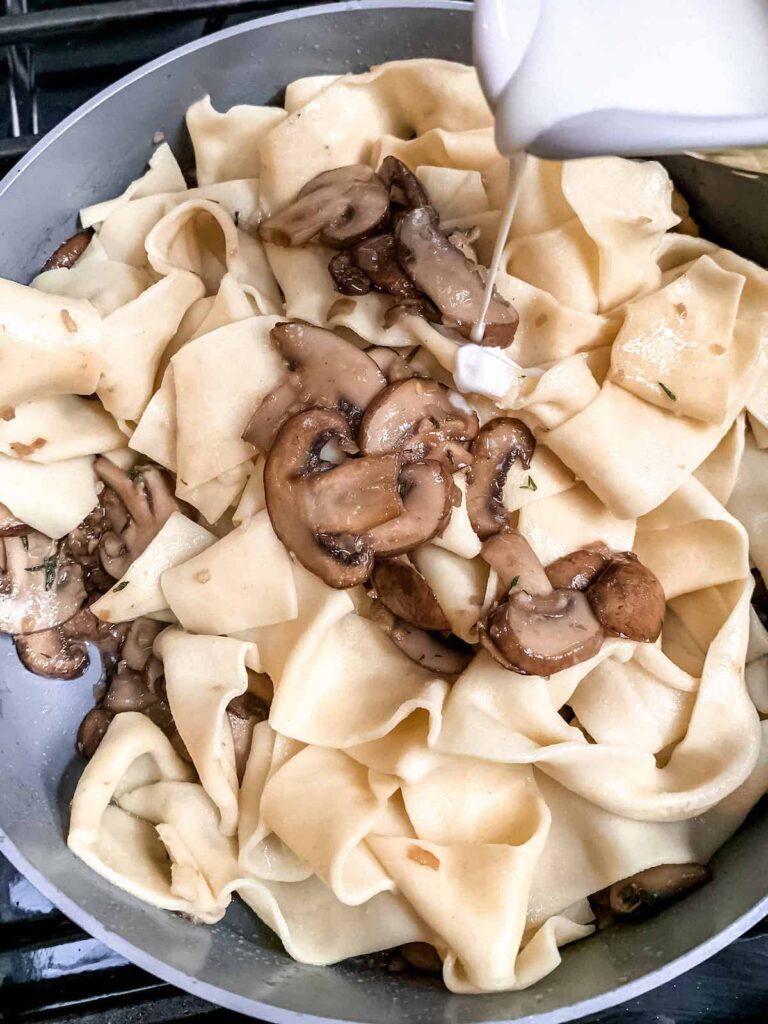 Pappardelle pasta with mushrooms and adding cream.