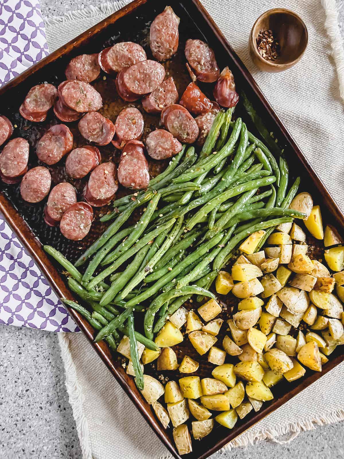 Copper sheet pan with sausage, potatoes and green beans.