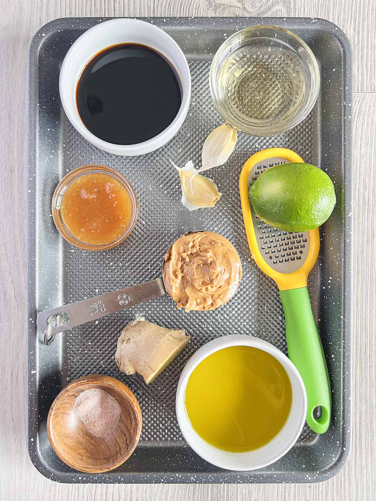 Ingredients for creamy peanut dressing on a silver baking sheet.