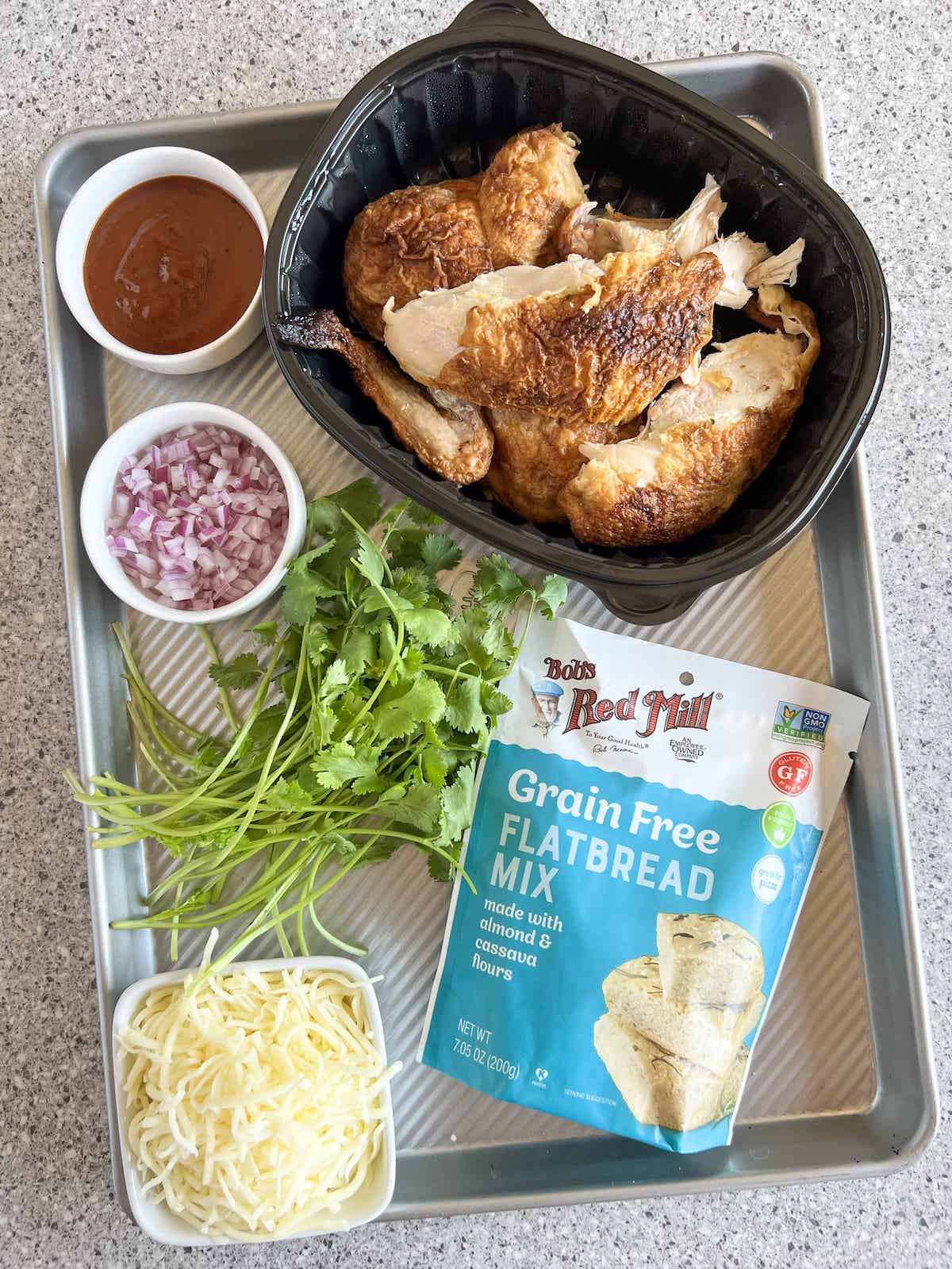 Ingredients for bbq chicken flatbread on a sheet pan.