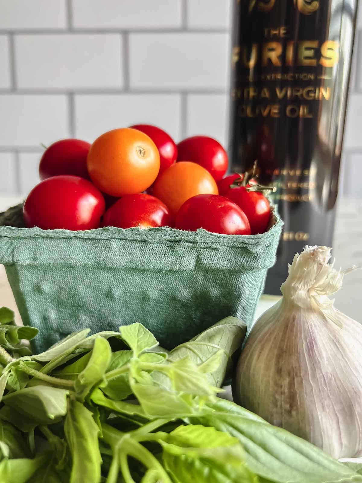 Basket of cherry tomatoes, head of garlic, fresh basil and olive oil in a black can.