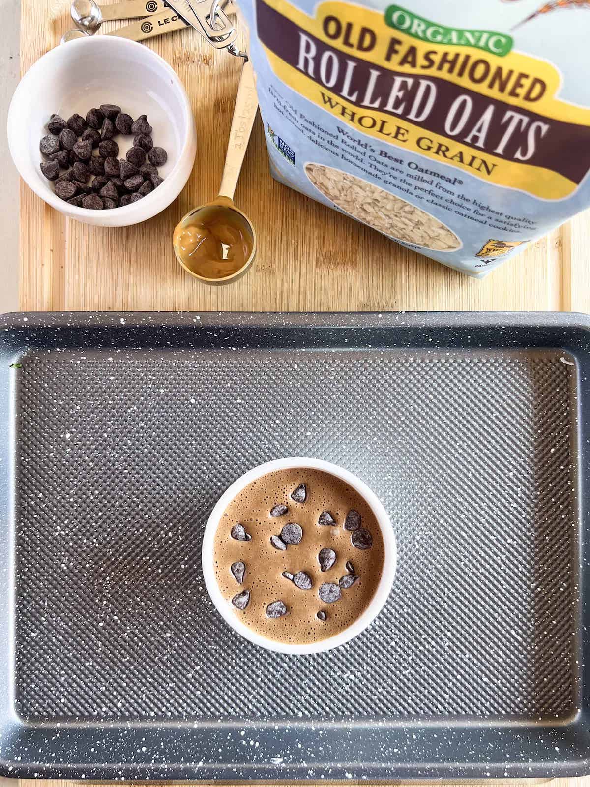 Baked oats batter in a ramekin on a baking sheet.