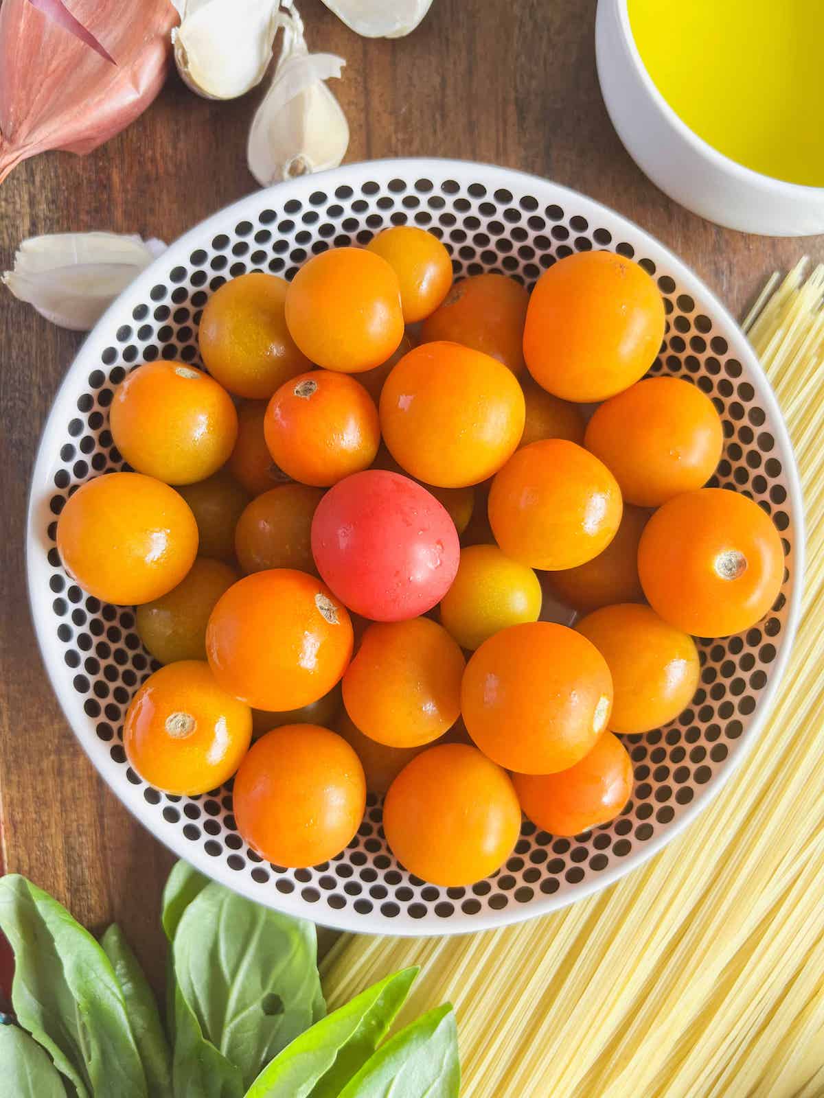 Black and white bowl full of sungold cherry tomatoes.