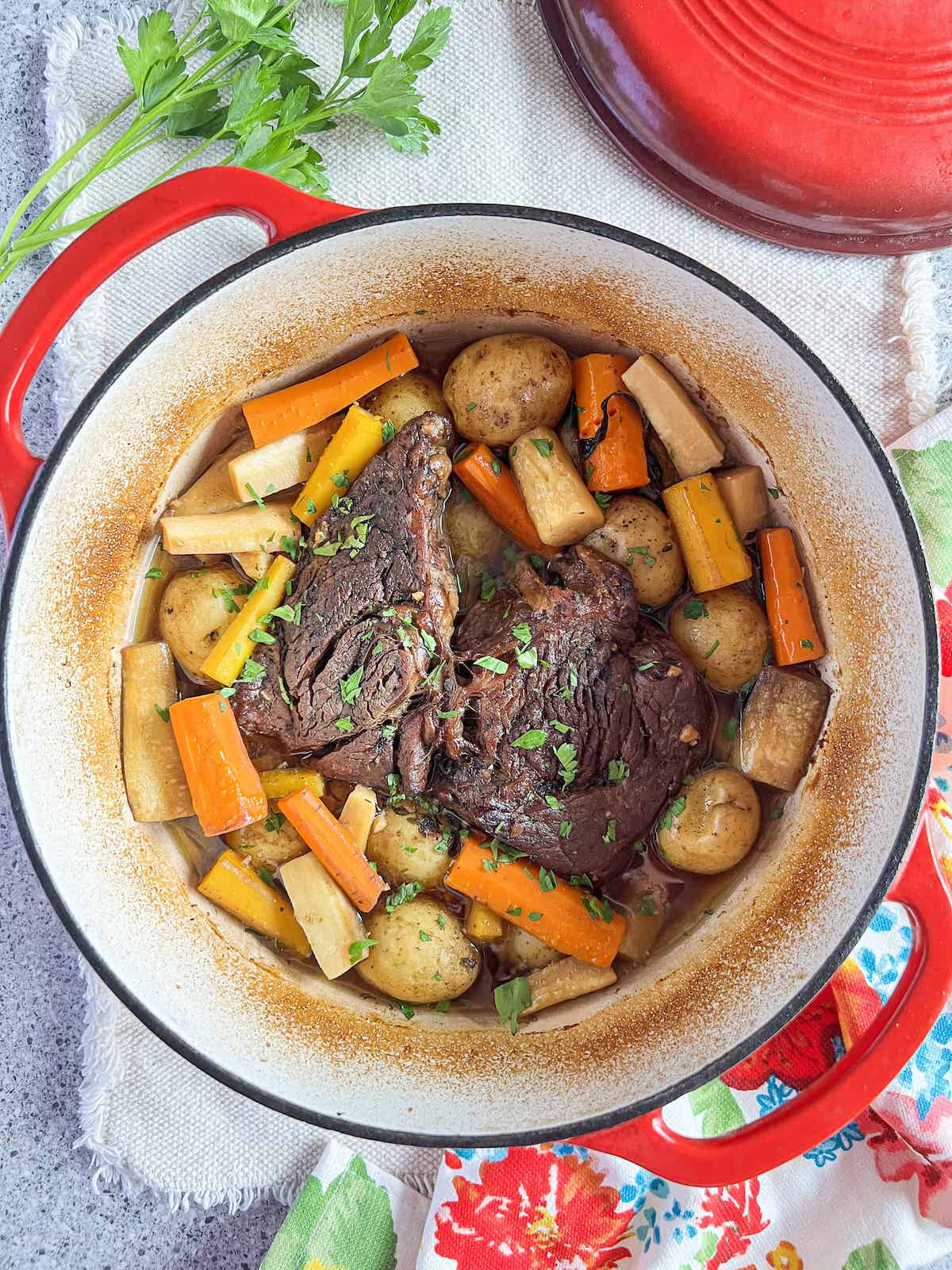Pot roast and veggies in a red dutch oven.