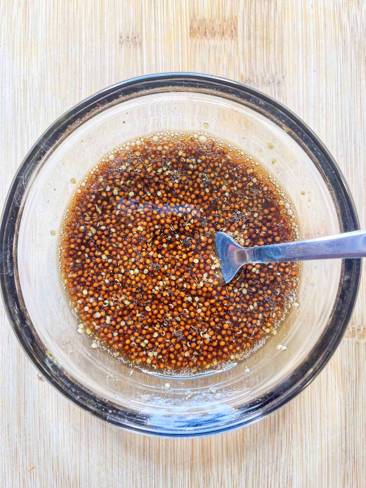 Whole grain honey mustard glaze in a glass bowl with a spoon.