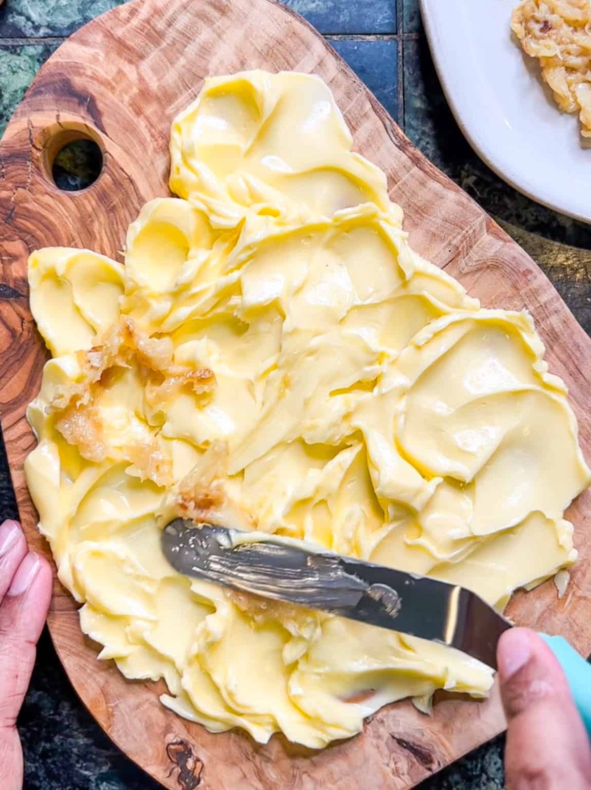 Spreading mashed roasted garlic on softened butter on a board.