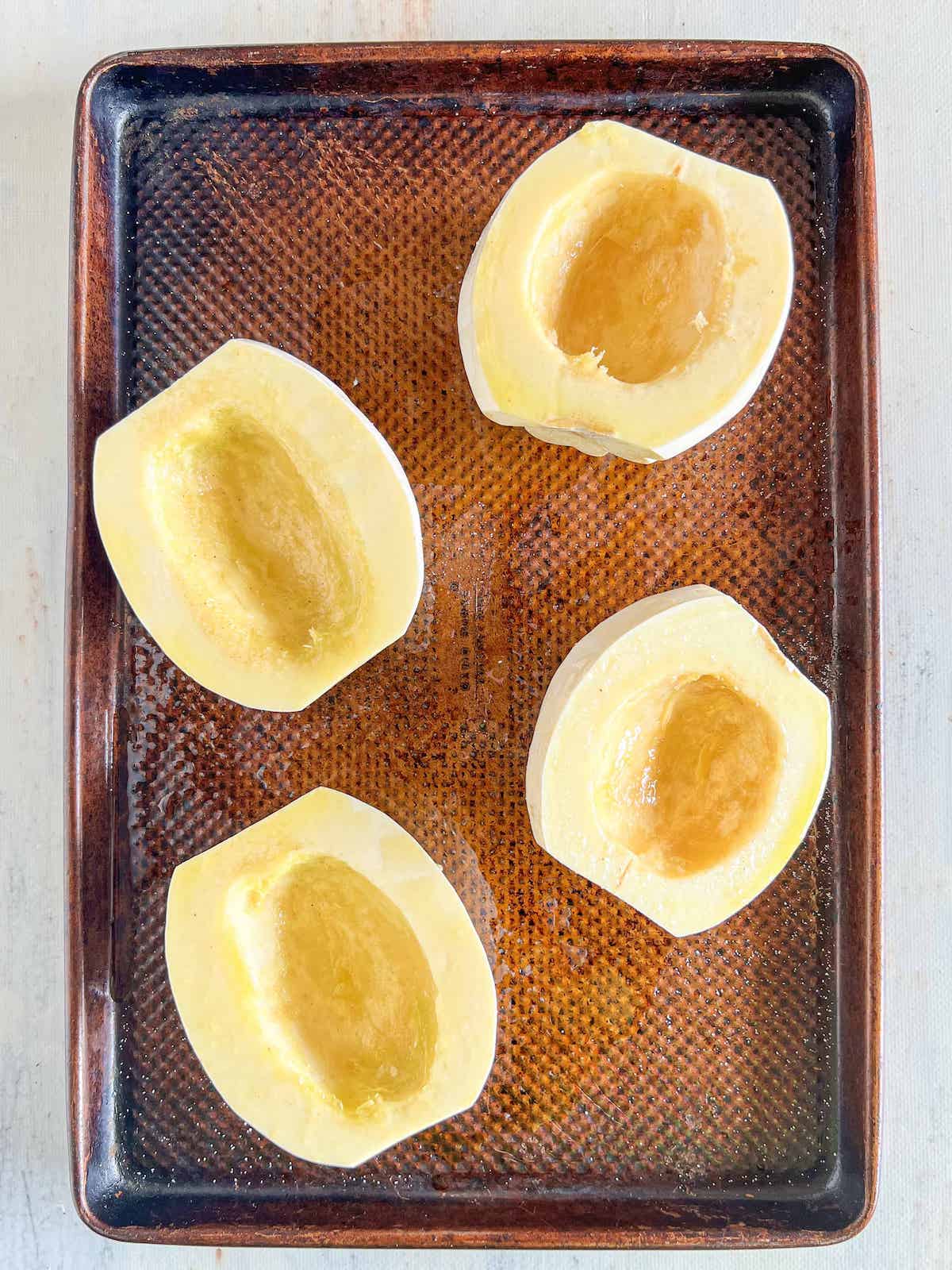 Mashed potato squash halves brushed with oil on a baking sheet.