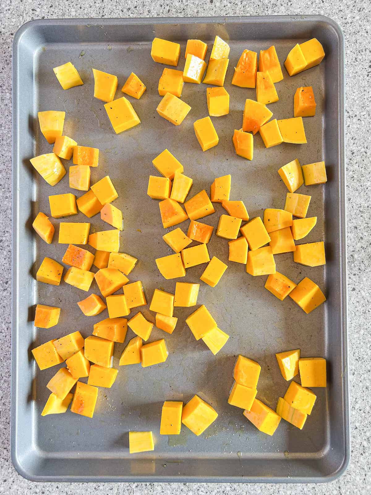 Cubed roasted butternut squash on a baking sheet.