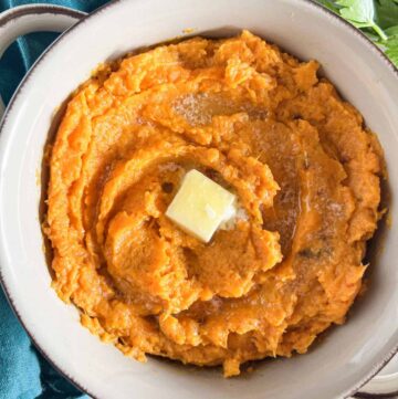 Chipotle mashed sweet potatoes topped with a pat of butter in a grey stoneware bowl.