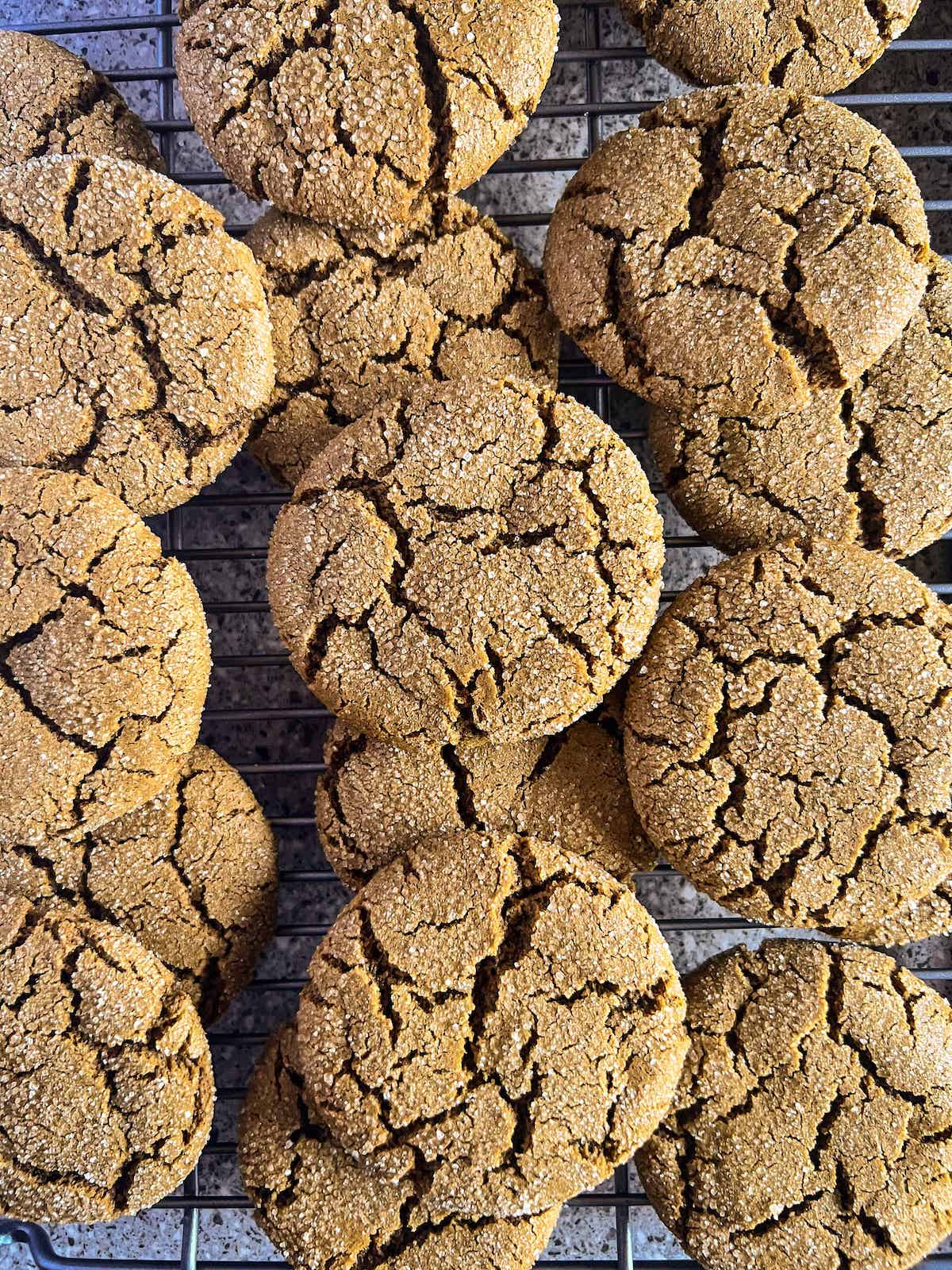 Molasses cookies piled on a wire cooling rack.