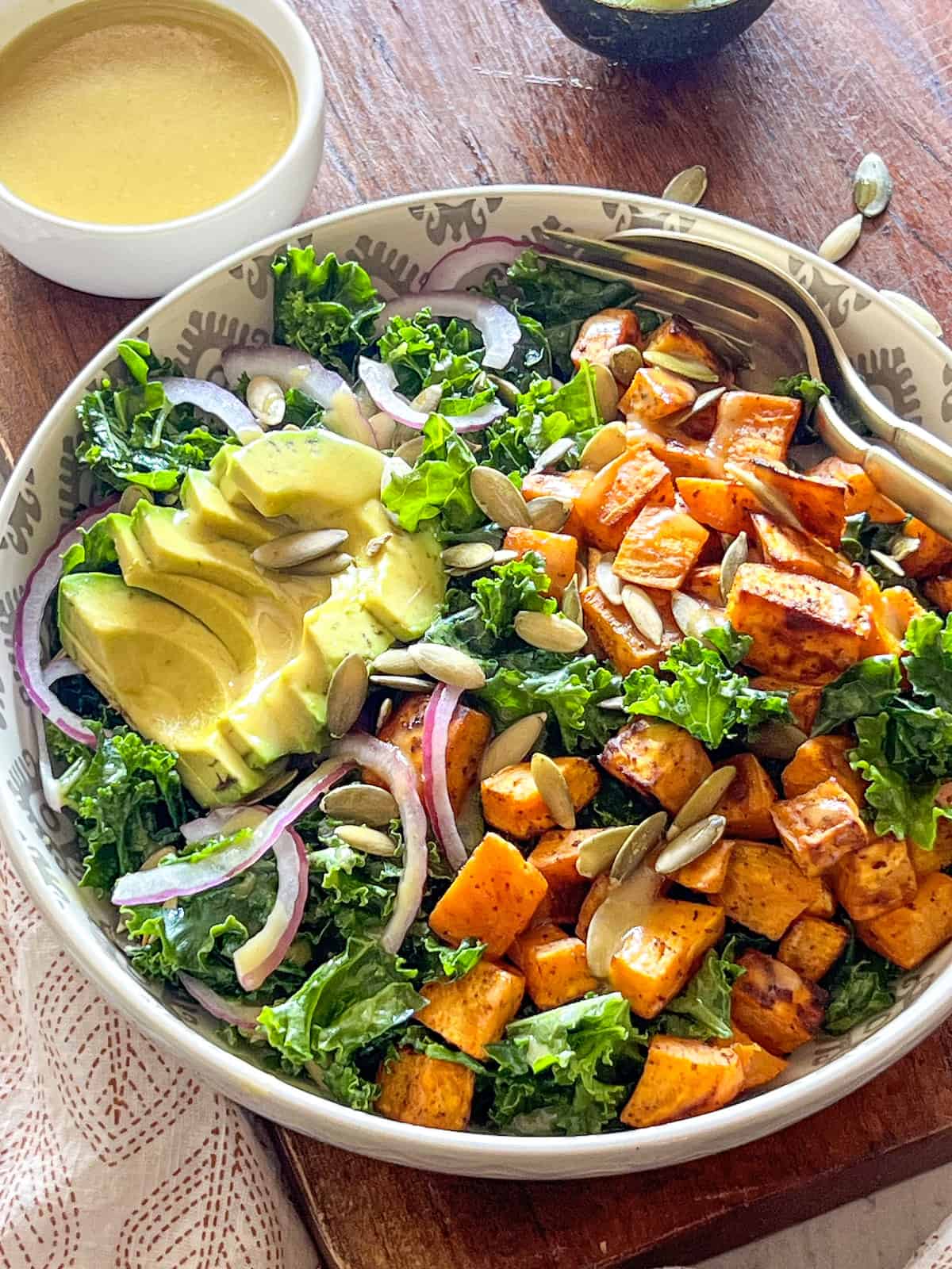 Finished salad in a white patterned bowl with a small dish of honey mustard dressing on the side.