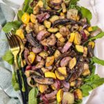 Balsamic Roasted Vegetable Salad on an oval platter with a gold spoon and fork.