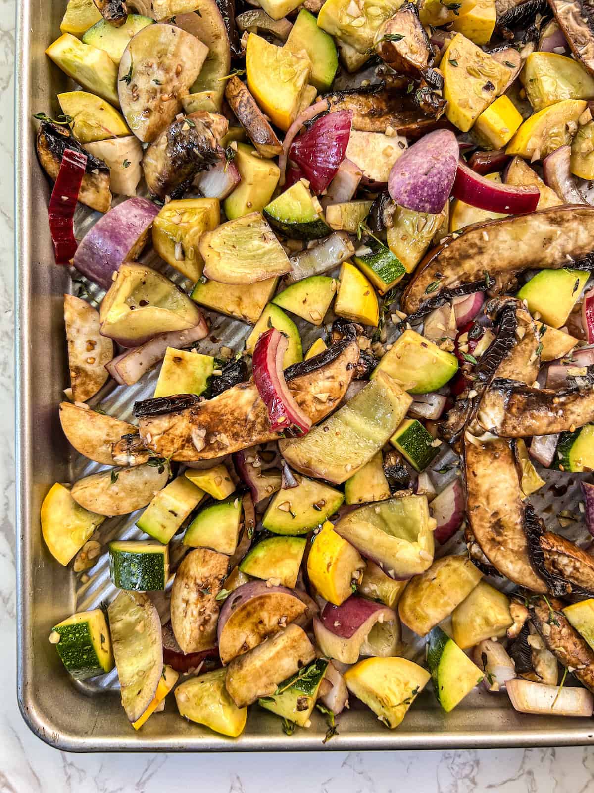Balsamic marinated vegetables spread out on a sheet pan.