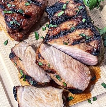 Sliced grilled pork chop on a wood cutting board.