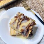 Square slices of cinnamon roll pancakes on a white plate with a gold fork.