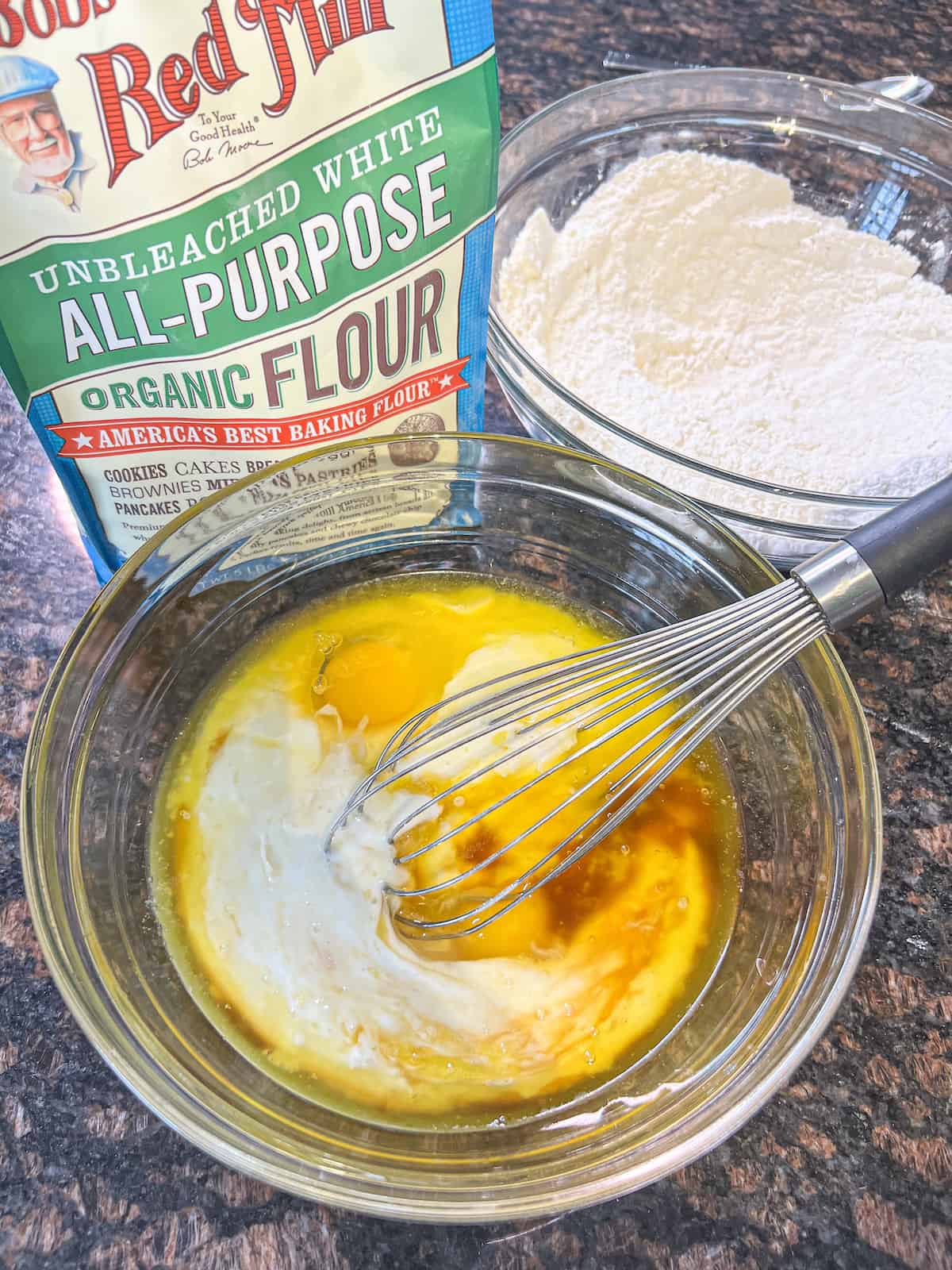 Melted butter, eggs, vanilla and buttermilk being whisked together in a glass bowl.