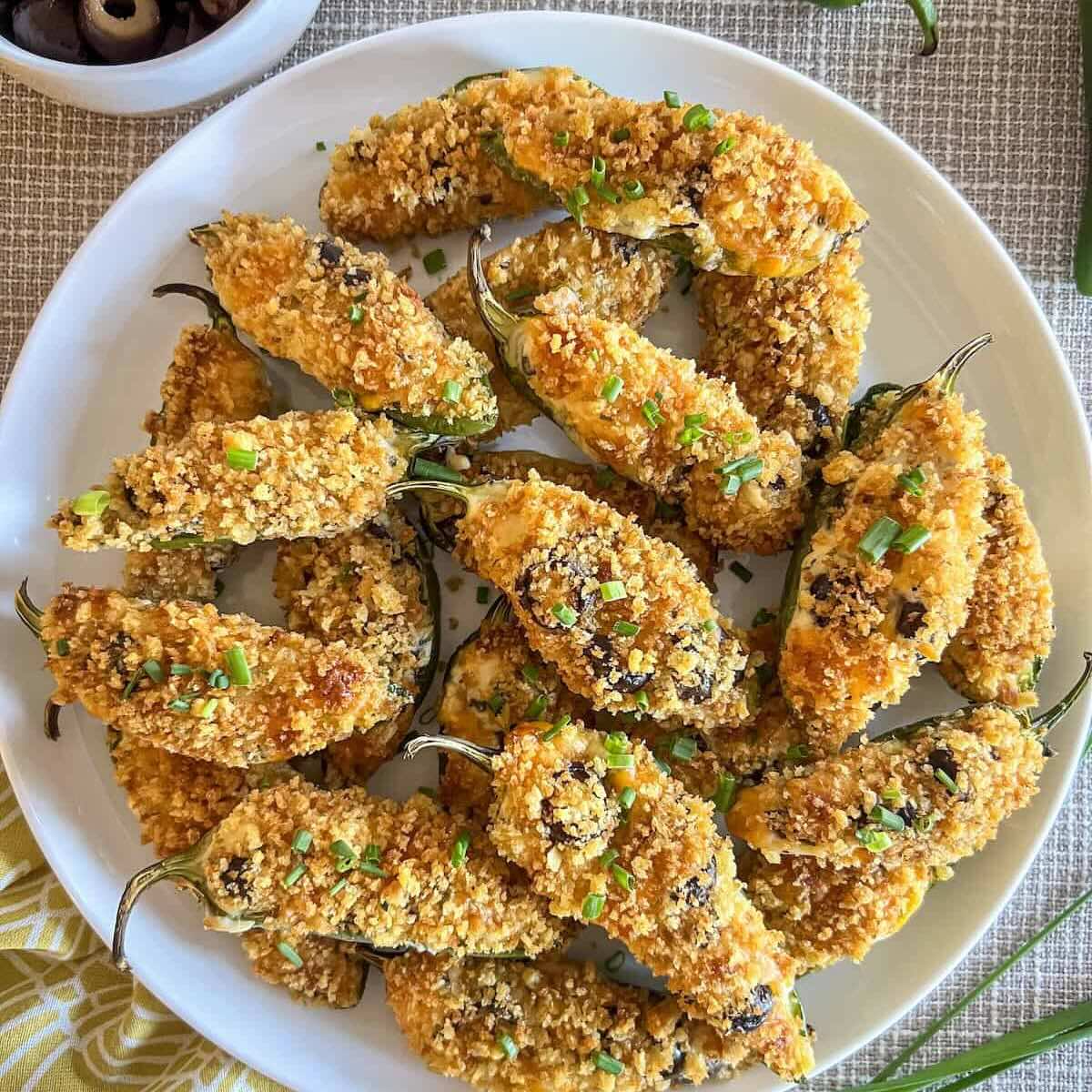 Jalapeno poppers with crispy panko topping on a white plate.