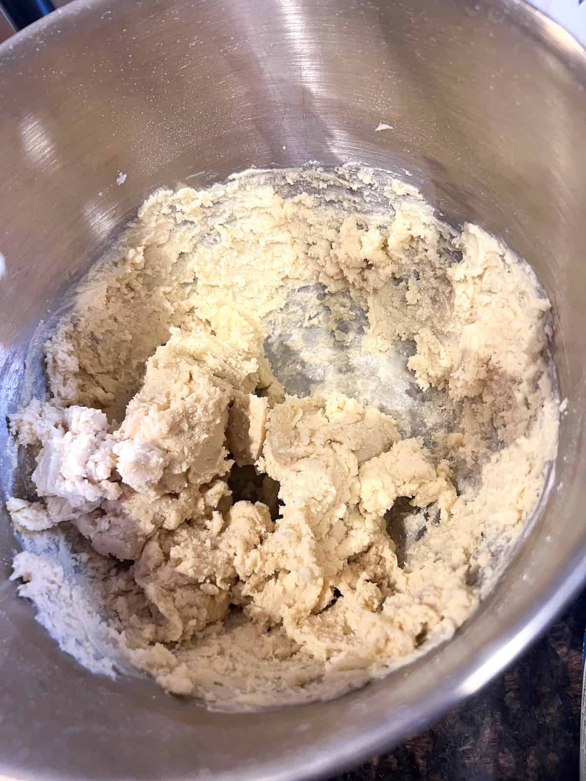 Flour mixed into butter mixture in the bowl of a stand mixer.