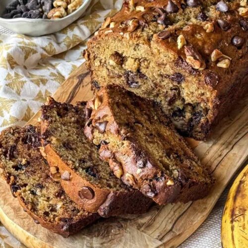 Thick slices of chocolate chip walnut banana bread on a wood cutting board.