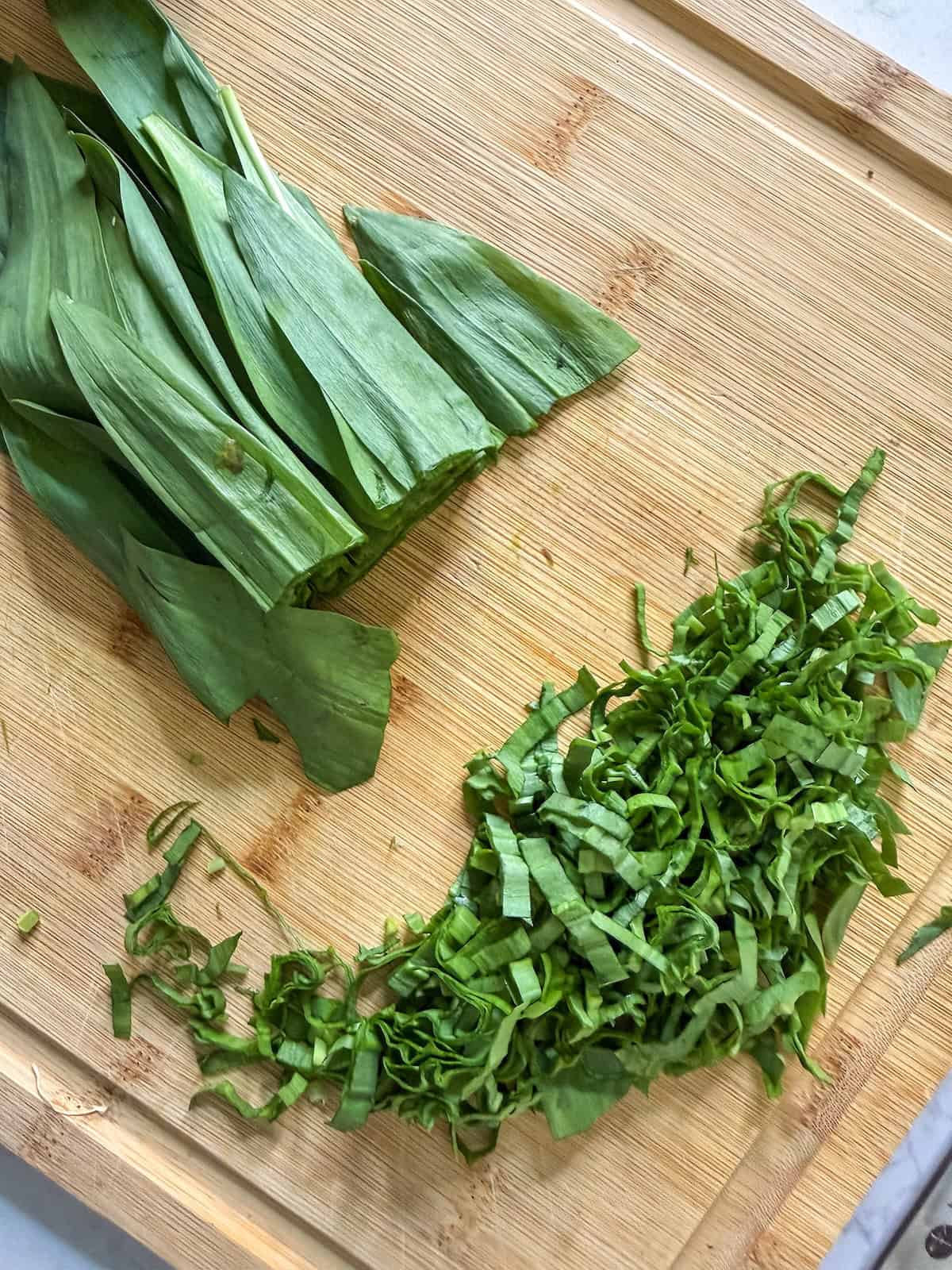 Thinly sliced ramp leaves on a wood cutting board.