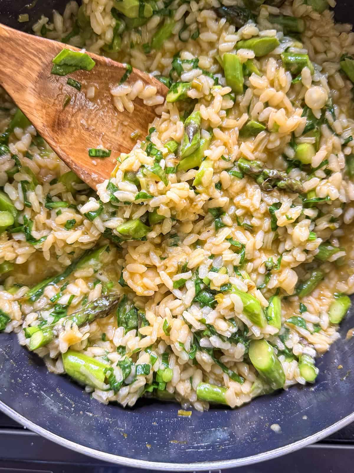 Finished risotto in a pan with a wood spoon.