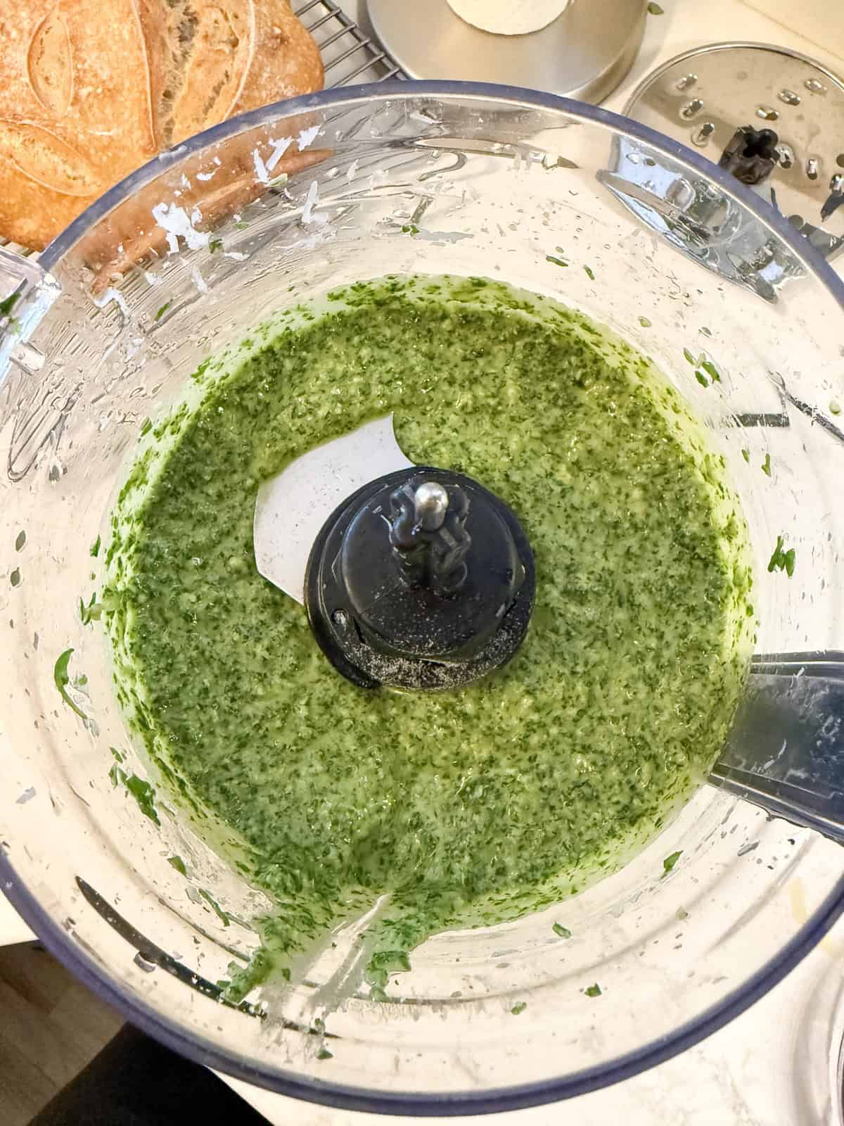 Arugula pesto in the bowl of a food processor.