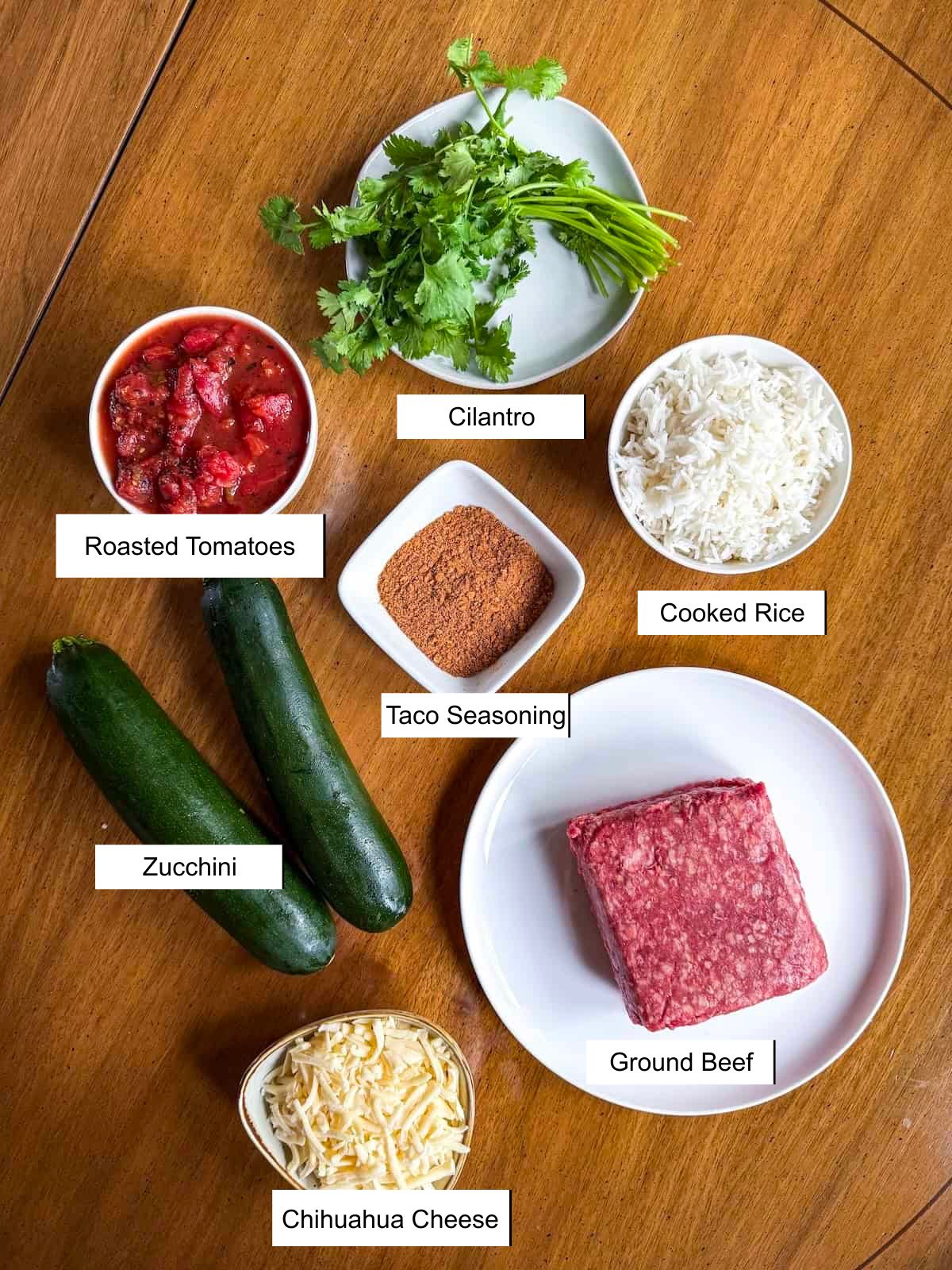 Labeled recipe ingredients in small dishes on a wood table.