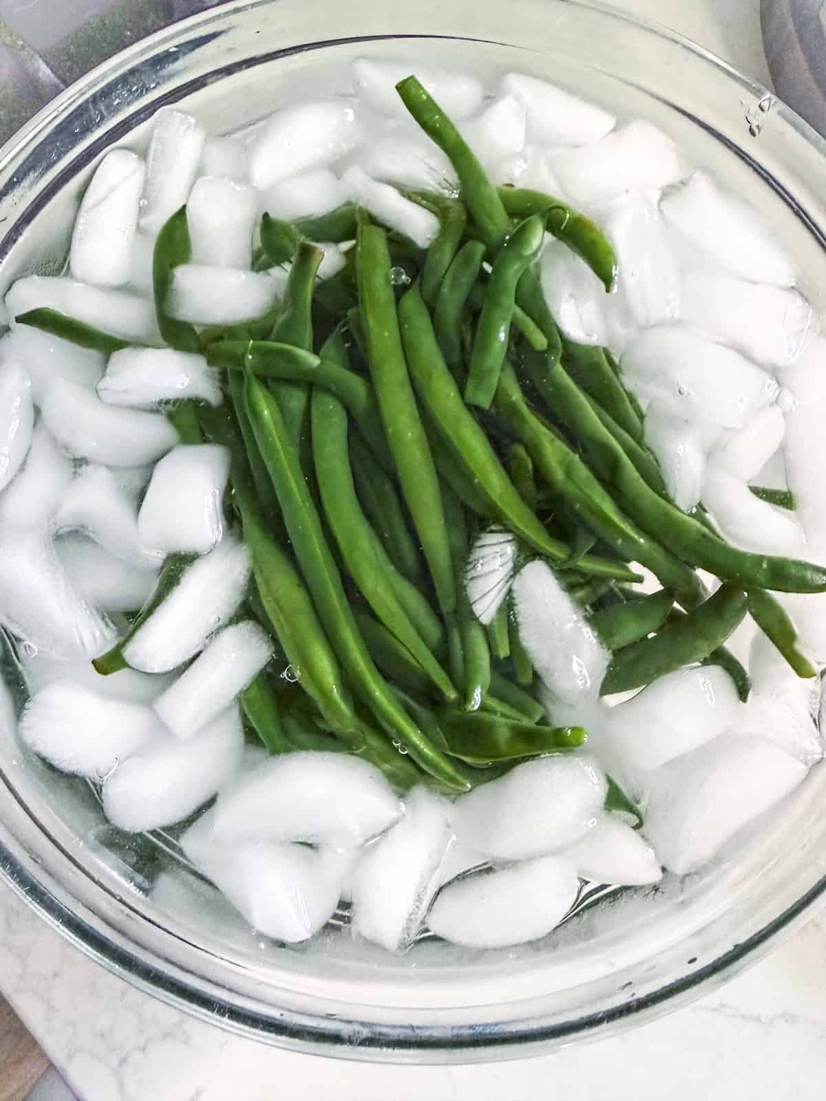 Blanched green beans in an ice bath.
