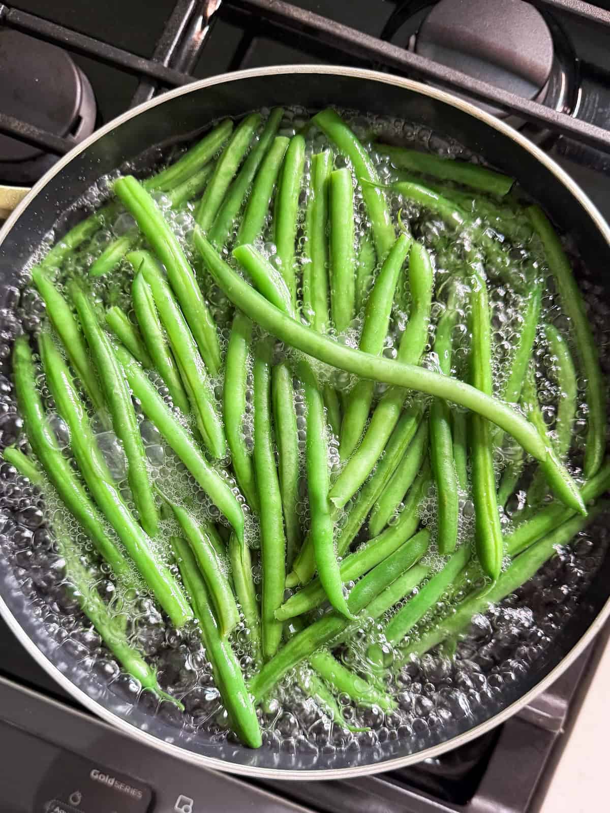 Blanching haricot vert in a pot of boiling water on the stove.